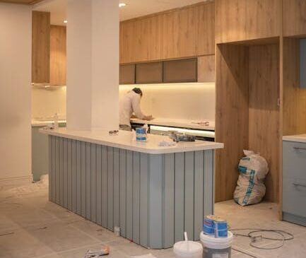 Contemporary kitchen undergoing renovation with wooden cabinets and clean design.